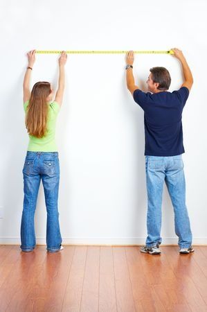 Pareja tomando con cinta métrica medidas de pared